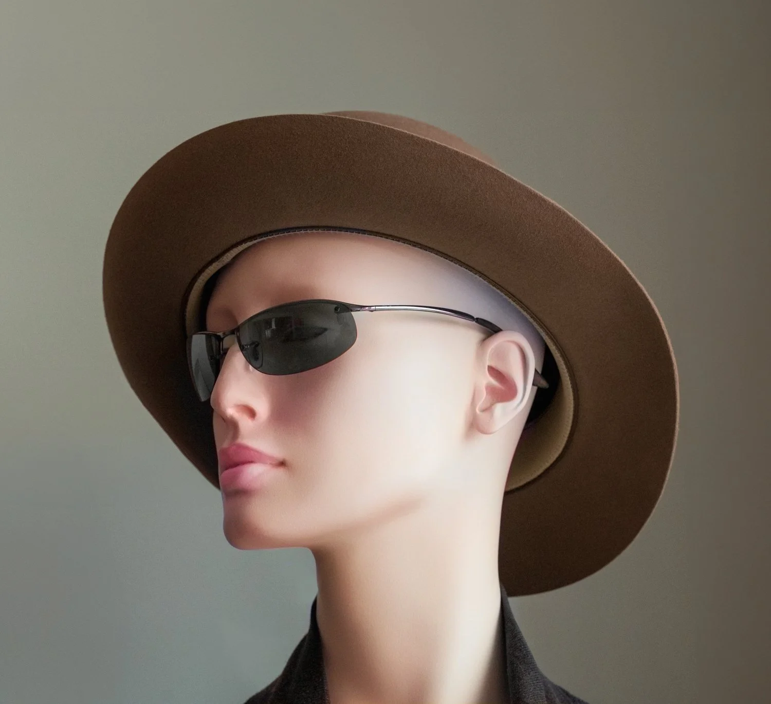 A mannequin head wearing a wide-brimmed brown hat and black sunglasses, facing slightly to the side against a plain background.