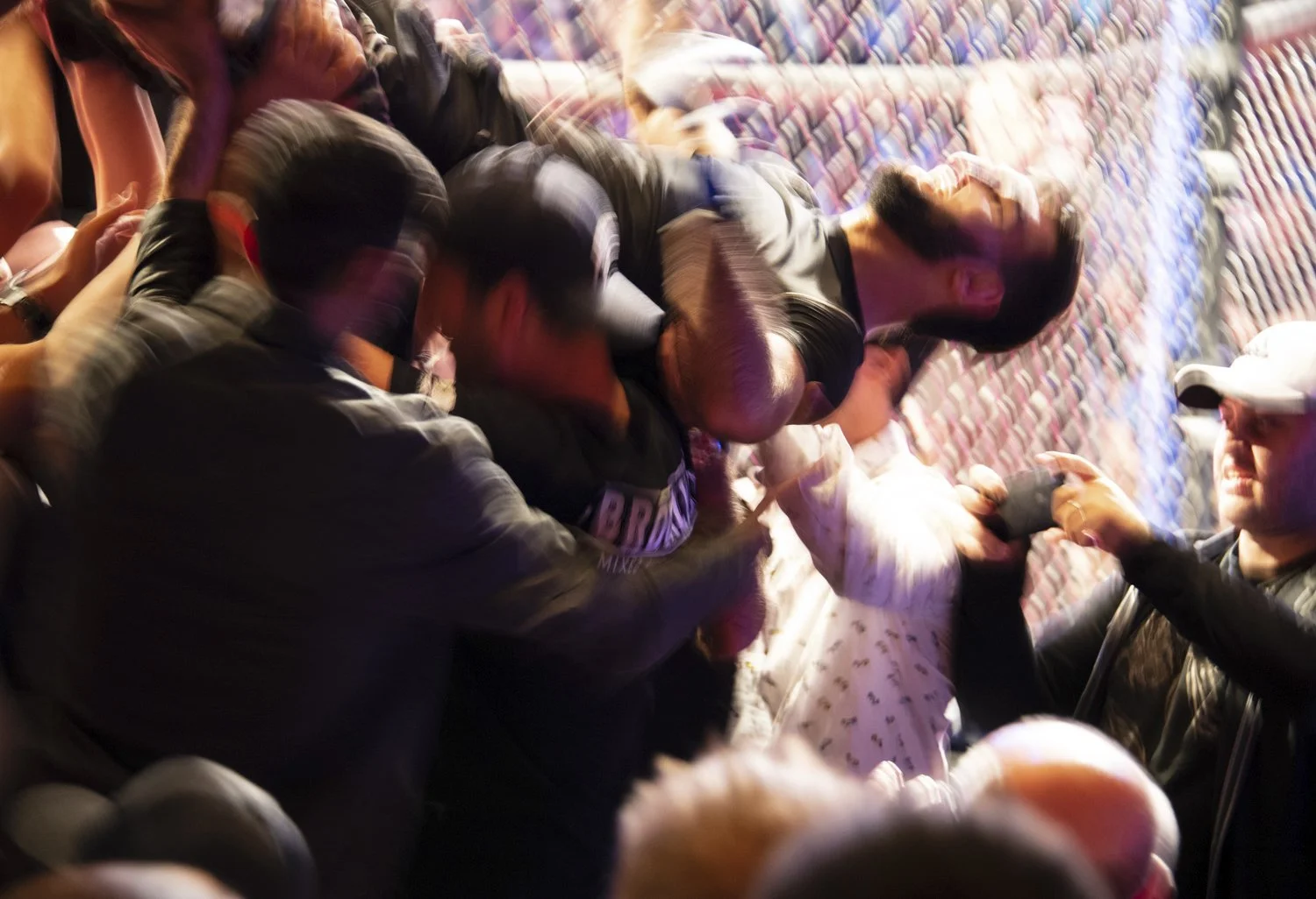 A group of people engaged in a physical altercation during a protest or riot, with some grappling on the ground and others involved in the confrontation.
