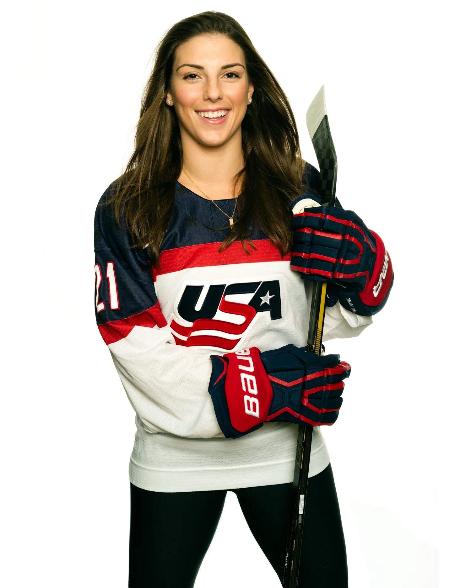 Olympic Gold medalist hockey forward Hilary Knight, posing in USA uniform holding a hockey stick, set against a white background.