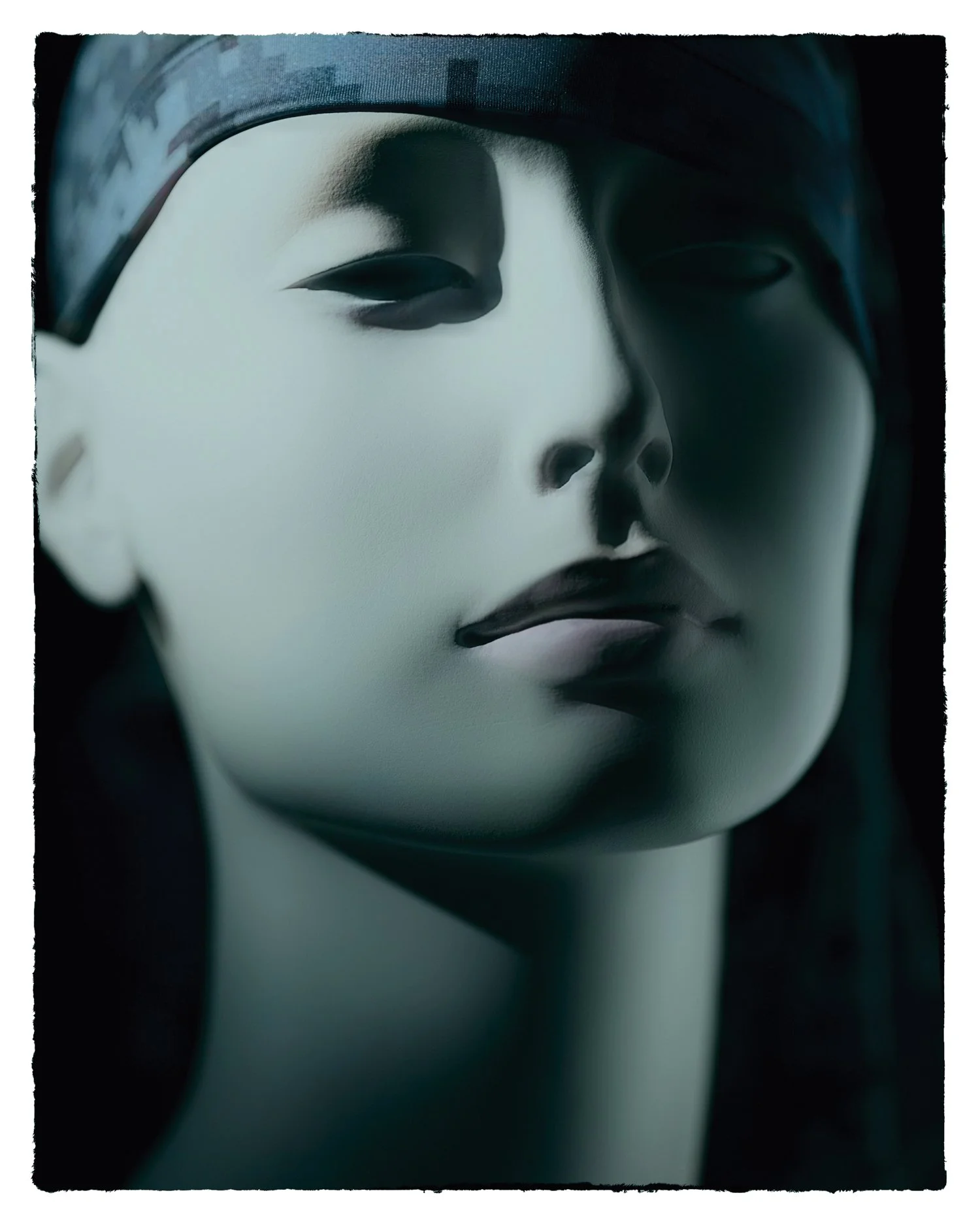 Close-up portrait of a mannequin evocative of a traditional Japanese Noh mask with a serene expression, pale face, and headwrap.