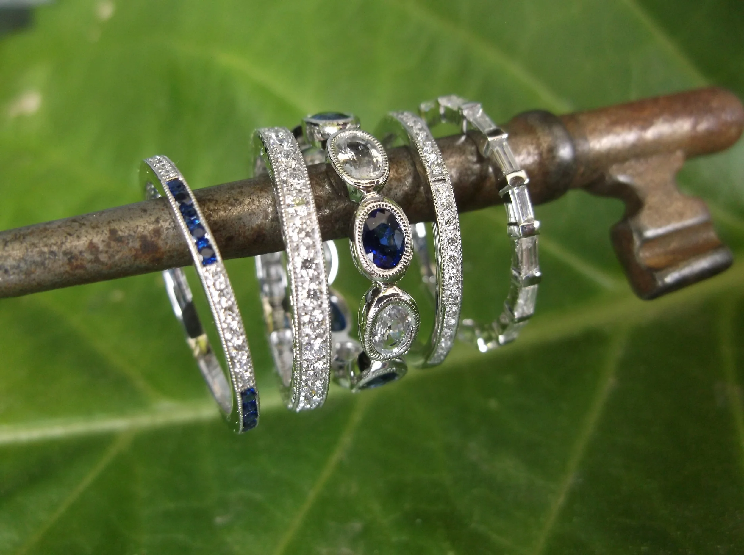 Gorgeous array of new bands! From Left to Right: Diamond and sapphire band set in 18K white gold; diamond eternity band with 0.52 carats total weight in diamonds set in platinum; blue sapphire and white sapphire oval eternity band set in 14K white gold; dainty diamond band set in 18K white gold; diamond baguette eternity band set in 18K white gold. 