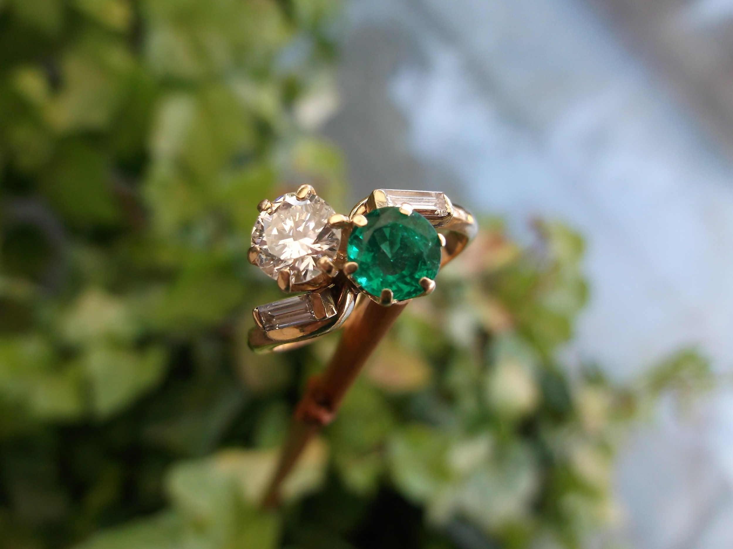 SOLD - Beautiful 1950's diamond and emerald bypass ring with a 0.80 carat round brillant diamond and a 0.70 carat emerald set in 14K yellow gold with baguette diamond detail. 