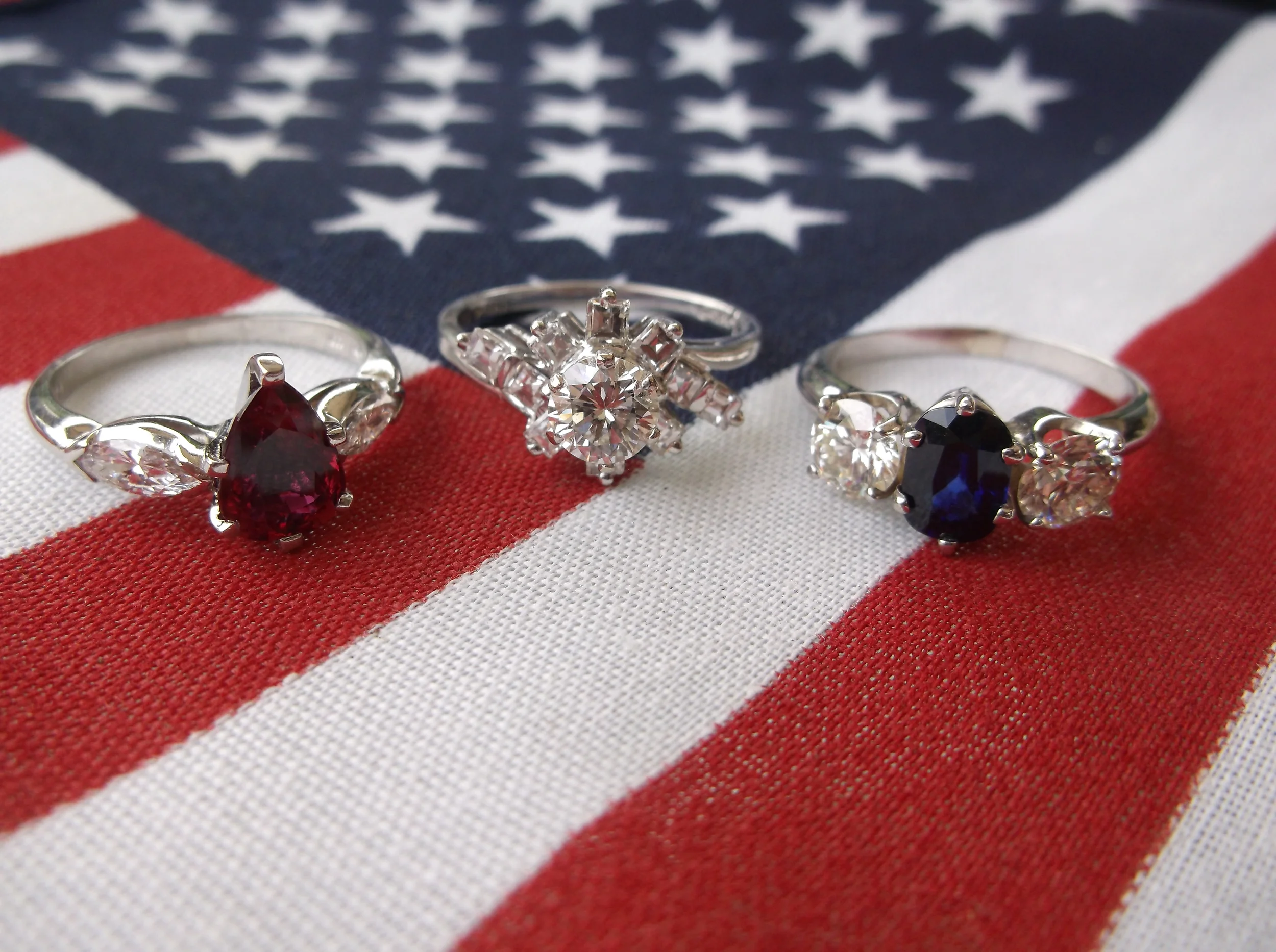 (Left) SOLD - 1.72 carat pear shaped ruby set in platinum with a marquis on either side. (Center) SOLD - 0.63 carat round brillant diamond in the center surrounded by diamond detail set in 14K white gold. (Right) SOLD - 1.22 carat sapphire with 0.62 carat and a 0.58 carat diamond on either side. 