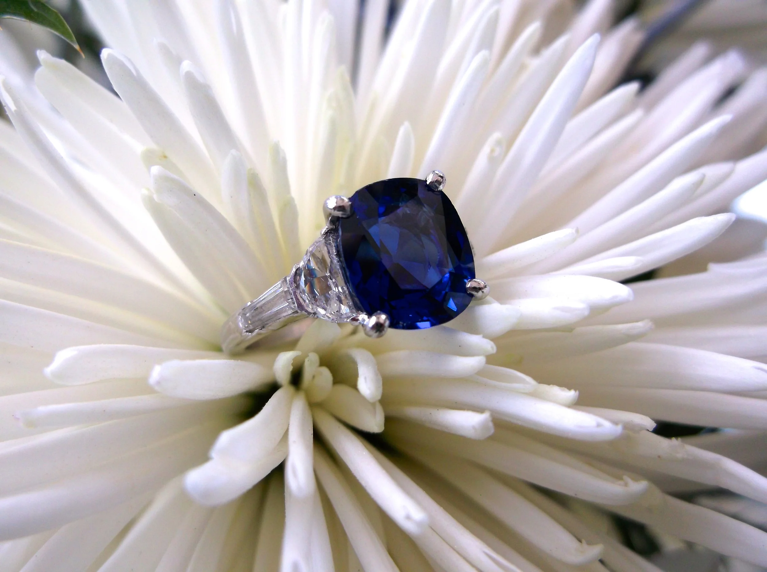 SOLD - Gorgeous 4.18 carat vibrant blue sapphire set in platinum with a baguette and half moon shaped diamond on either side. 