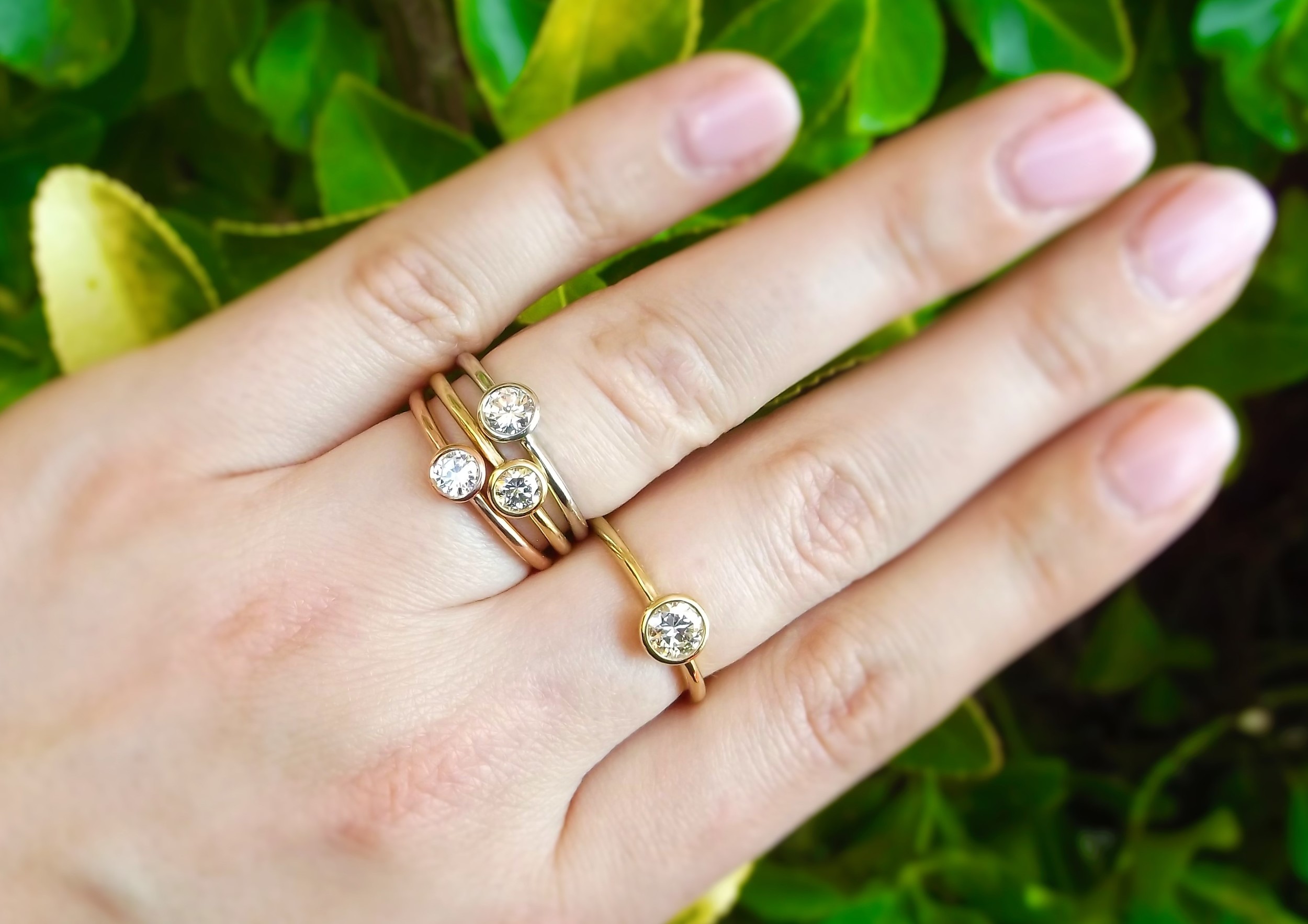 Lovely bezel set diamond rings in white gold, rose gold and yellow gold. The diamonds set in the three stacked rings range from 0.24 carats to 0.33 carats. The individual yellow gold diamond ring is 0.54 carats.