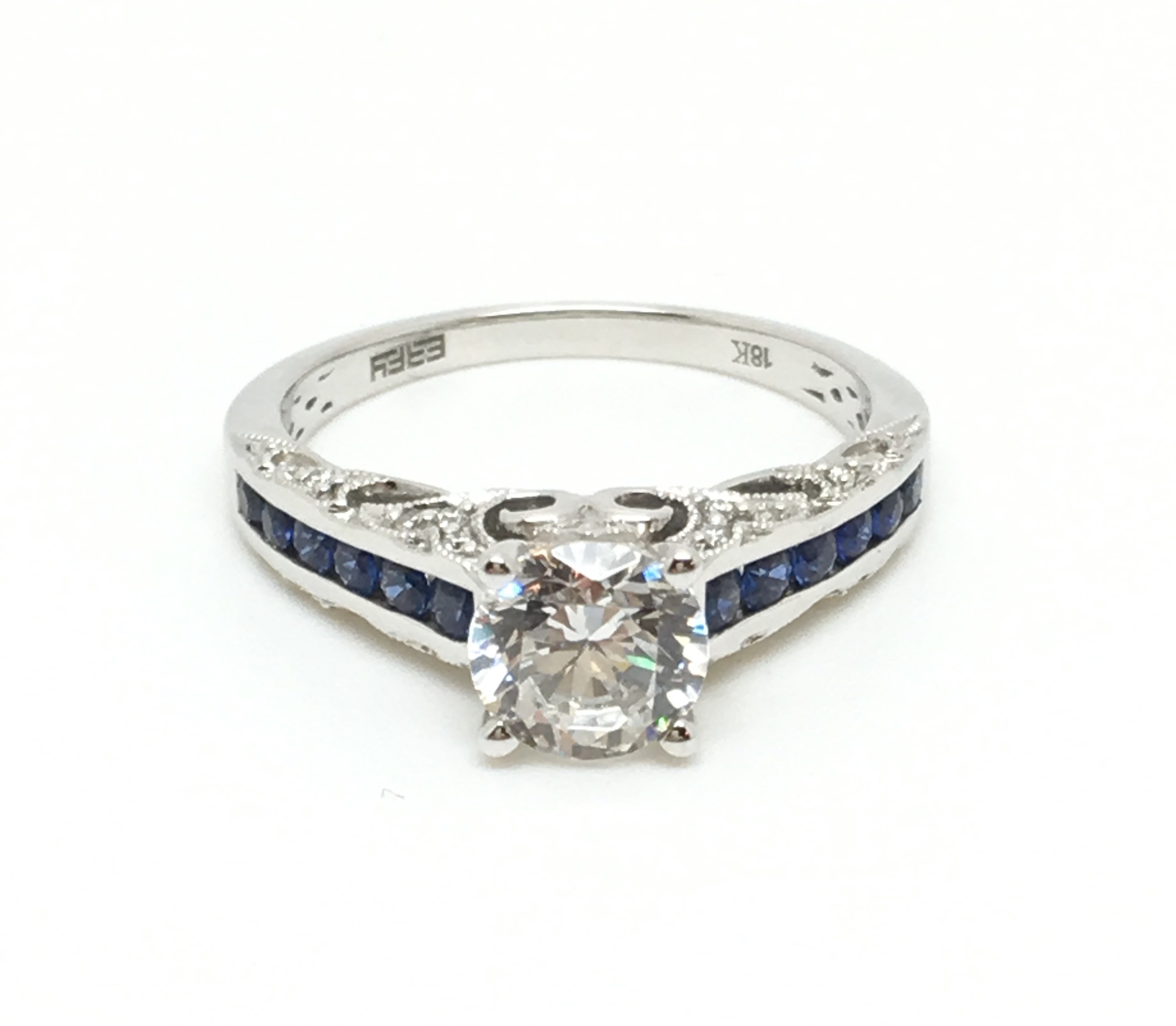 Does your diamond need an upgraded look? This gorgeous 18K white gold and blue sapphire mounting is available in our sale! (Pictured here with a CZ in the center to help visualize what your stone will look like set in the setting. The setting will accommodate a one carat center diamond. )