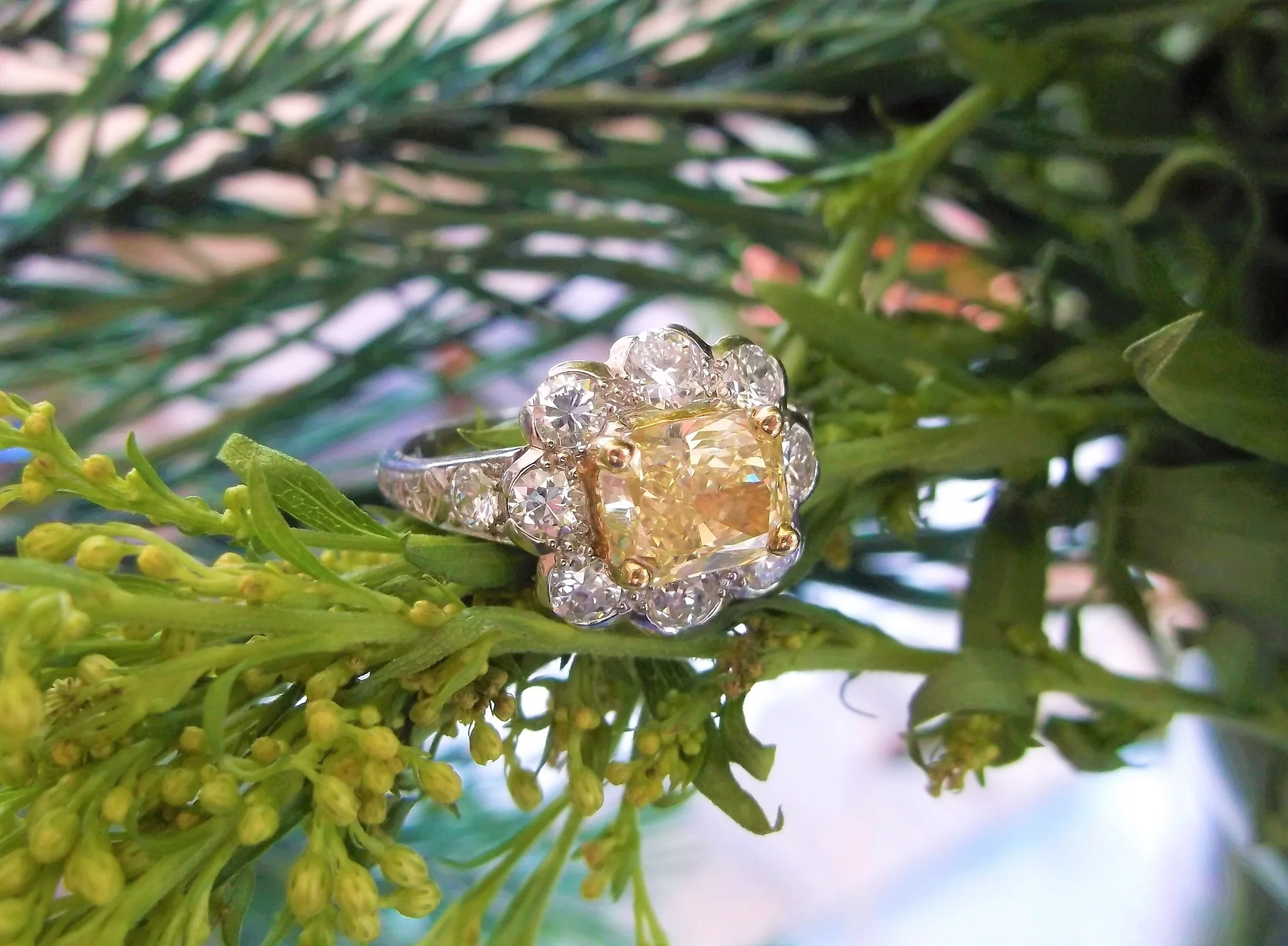 SOLD - Enchanting 1.61 carat yellow diamond set in a platinum mounting with 1.25 carats total weight in round brilliant cut diamonds. 