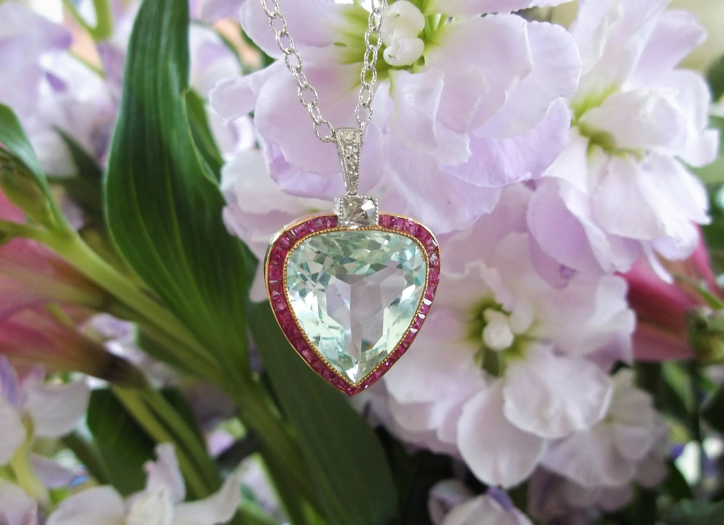 SOLD - Take her breath away with this heartfelt Edwardian era, platinum topped gold pendant, set with a gorgeous center 8.00 carat aquamarine surrounded by 1.00 carat total weight in french cut rubies and Old Mine cut diamond details. 