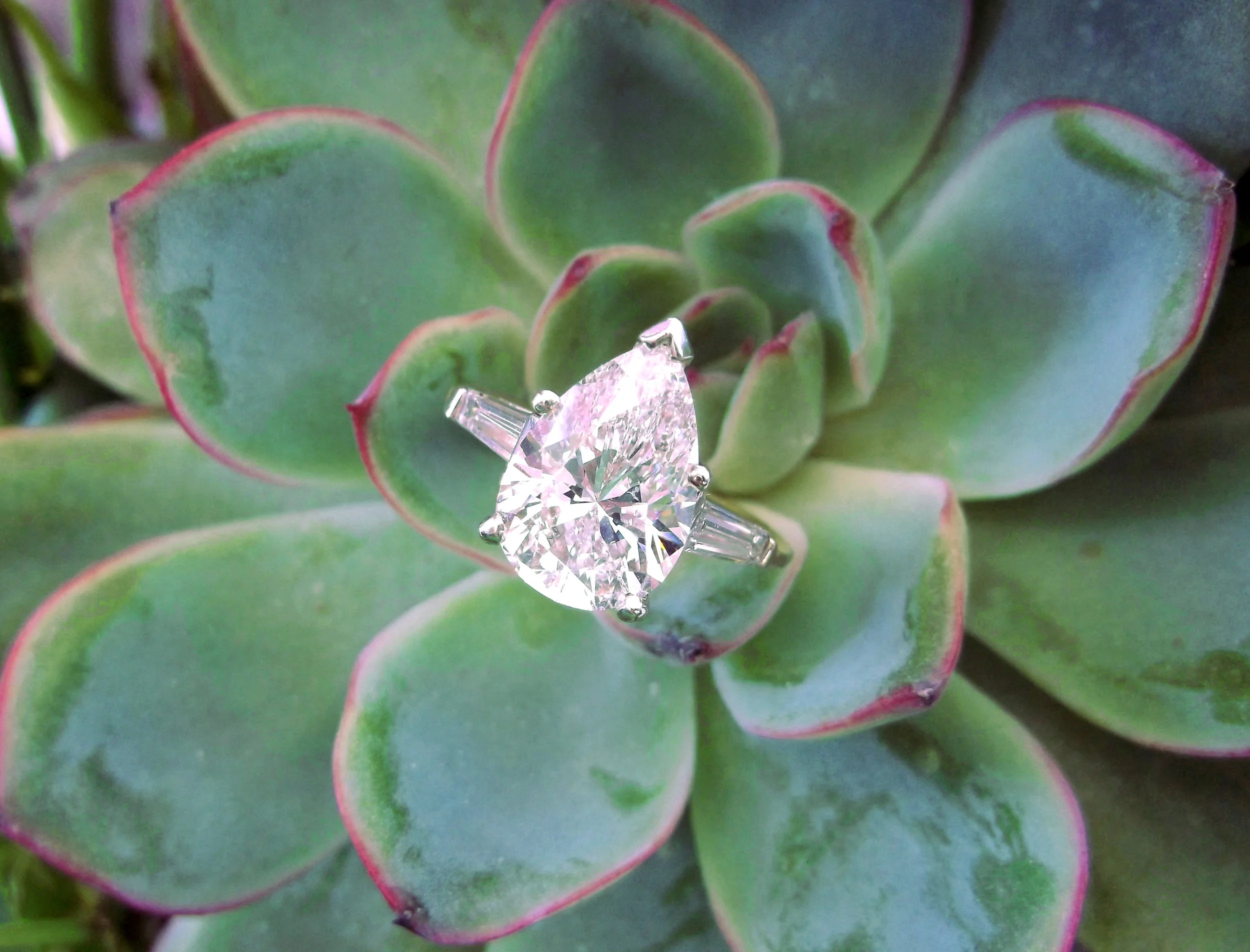 A glamorous 3.02 carat pear shaped diamond set in a white gold mounting with baguette cut diamond details.