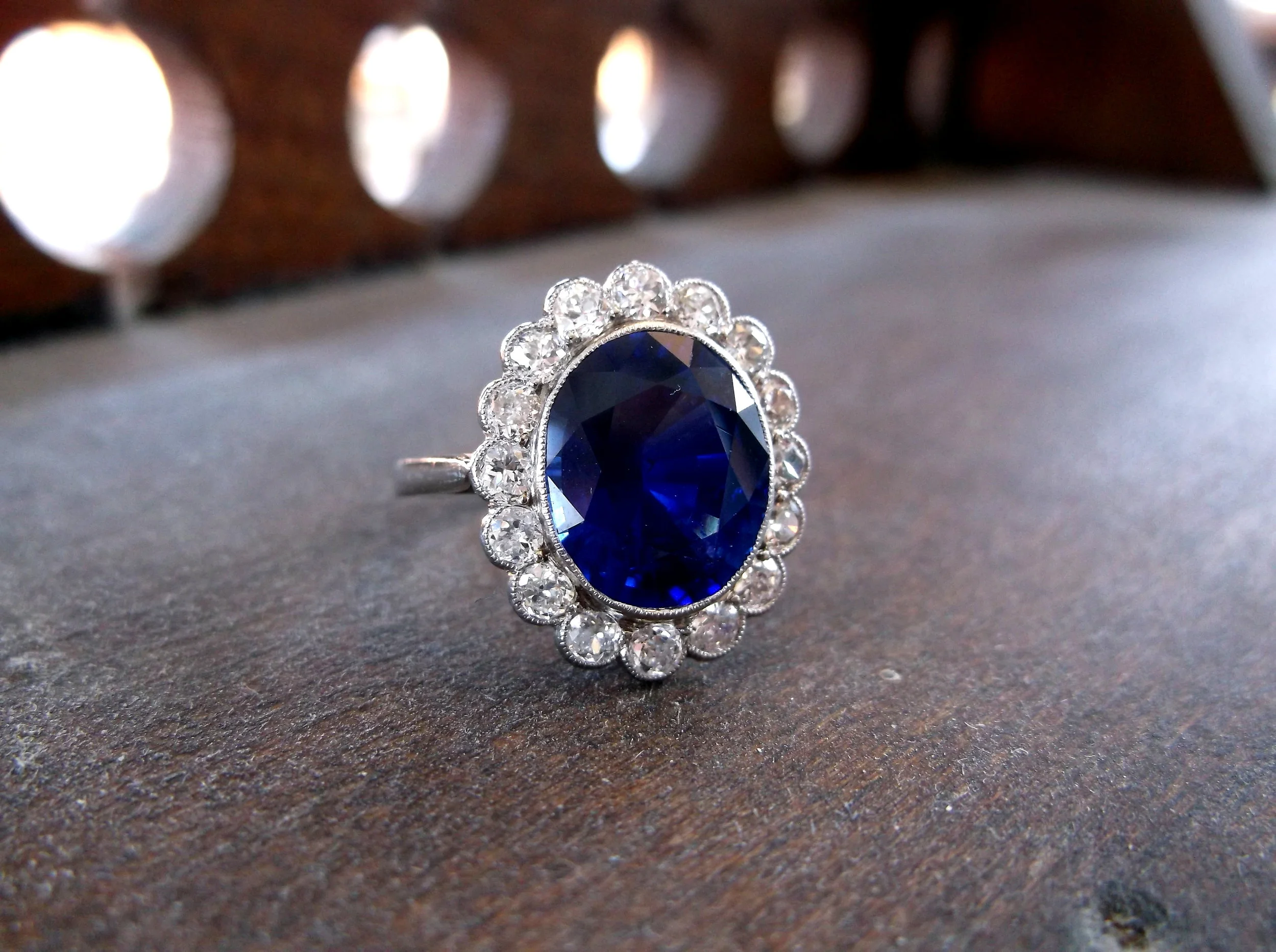 SOLD - Vibrant and captivating 4.50 carat oval blue sapphire, surrounded by 0.75 carats total weight in Old Mine diamonds. 