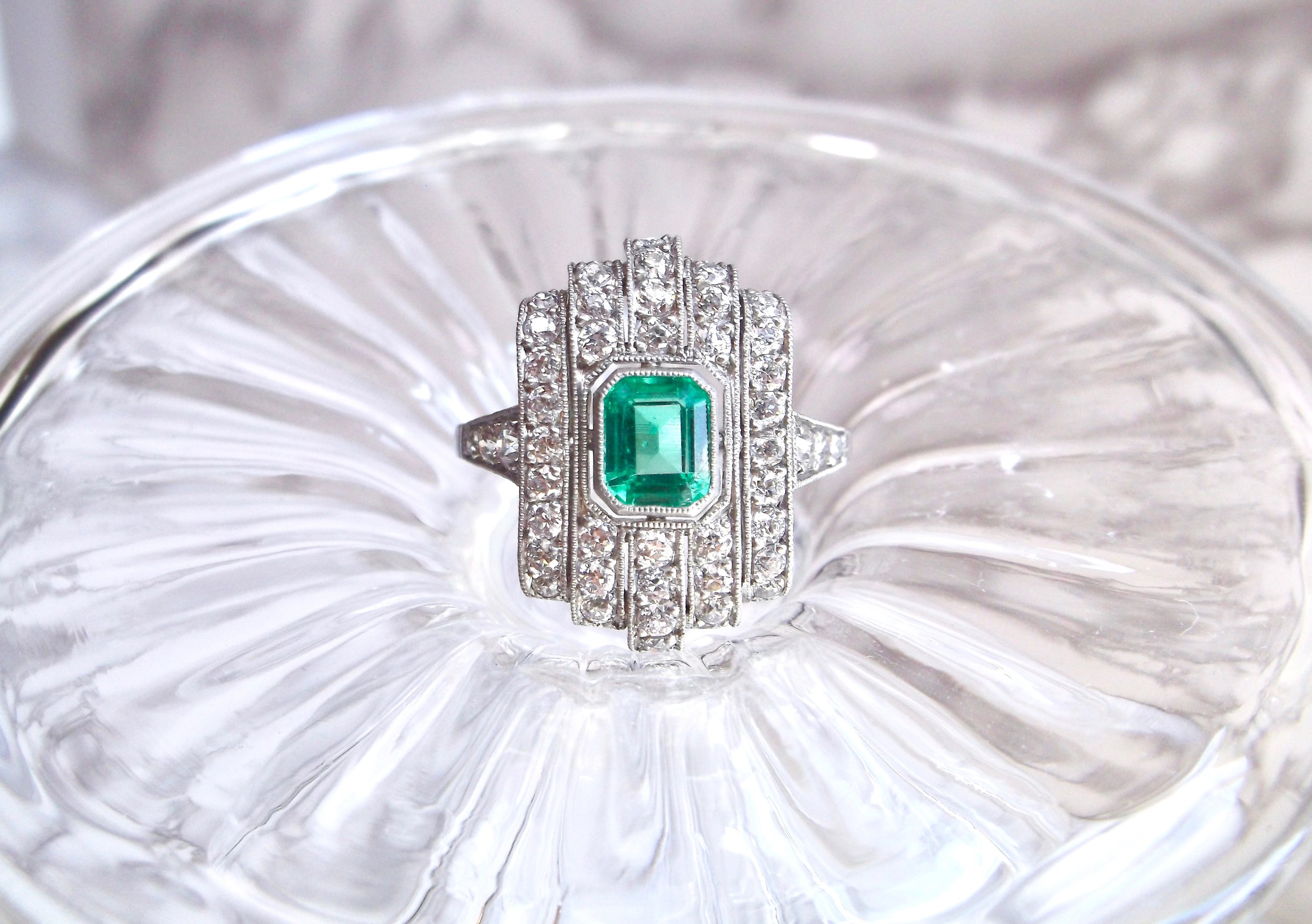 The Art Deco beauties keep rolling in! This gorgeous emerald, diamond and platinum ring features a center 0.65 carat step cut emerald, surrounded by 1.00 carats in Old Mine cut diamonds with gorgeous filigree details underneath! See all the angles HERE