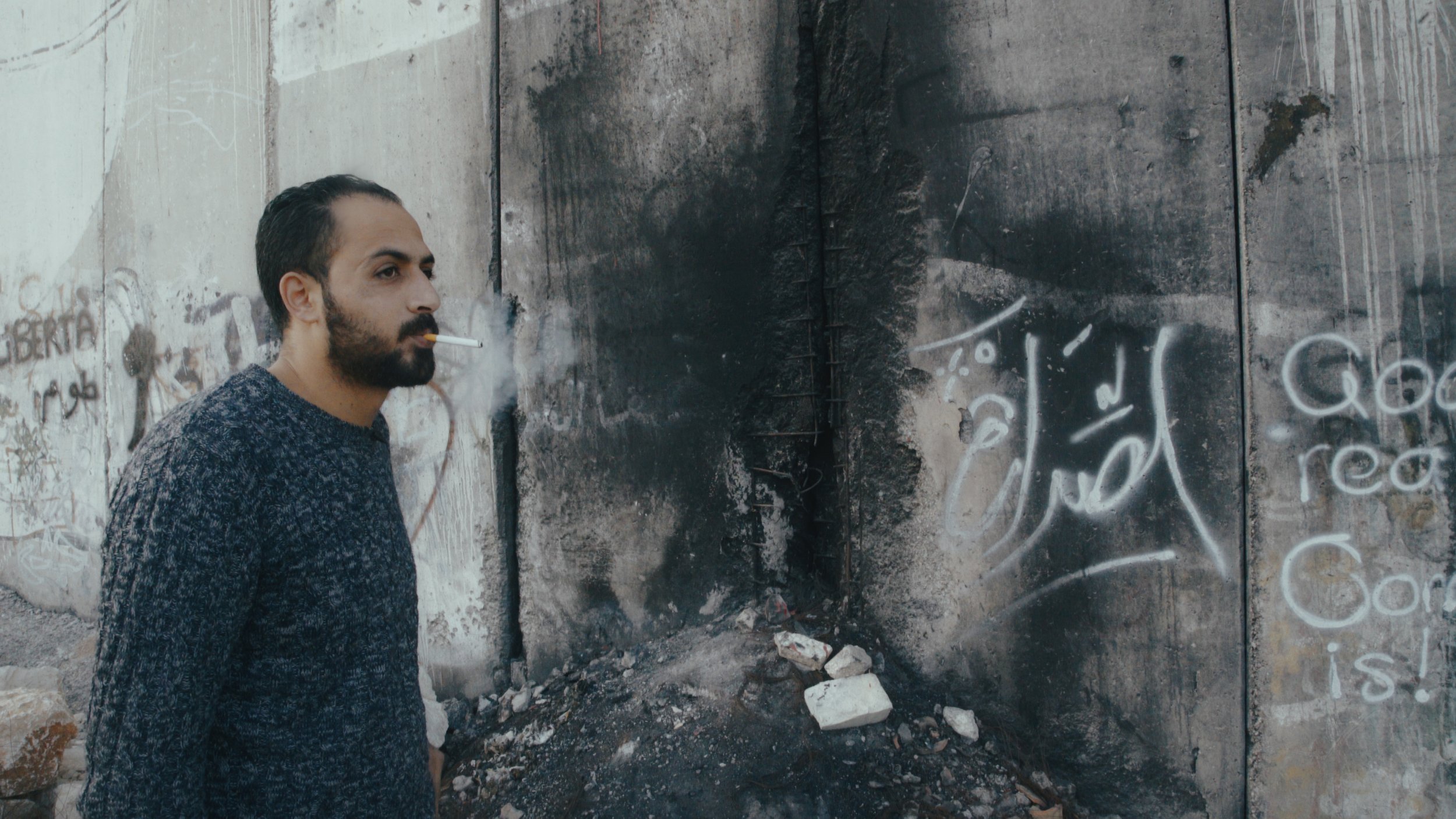 Mohammad Alazza at the base of the Israeli Separation Wall. Courtesy: Hurdle