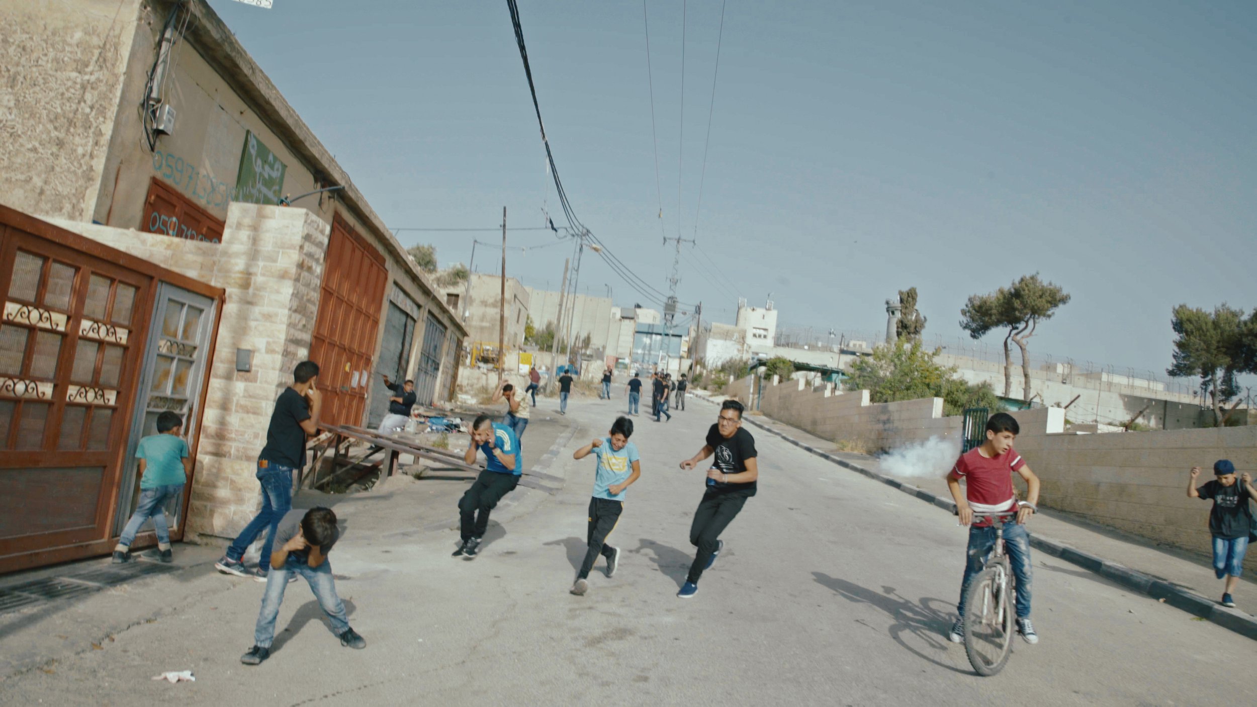 Youth of Aida Refugee Camp run to avoid the blast of a concussion grenade. Courtesy: Hurdle