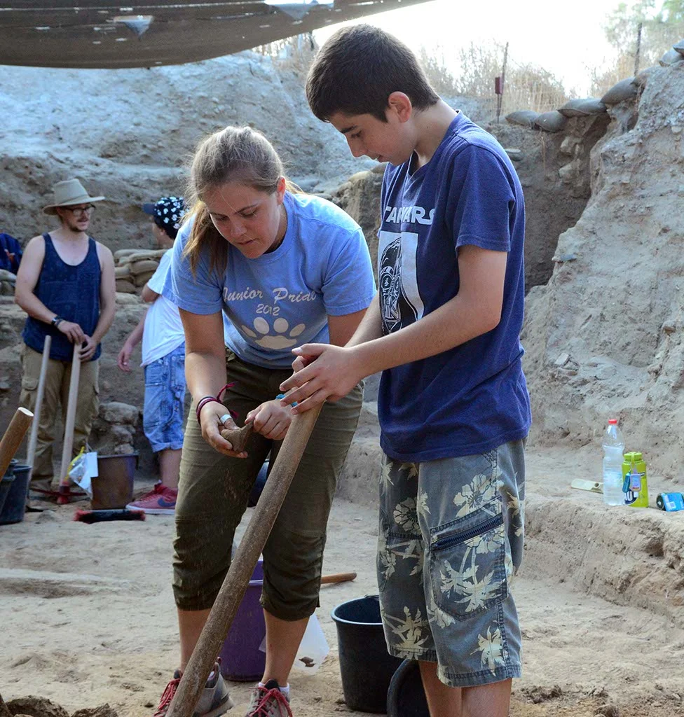 A volunteer discusses some pottery with an Israeli student