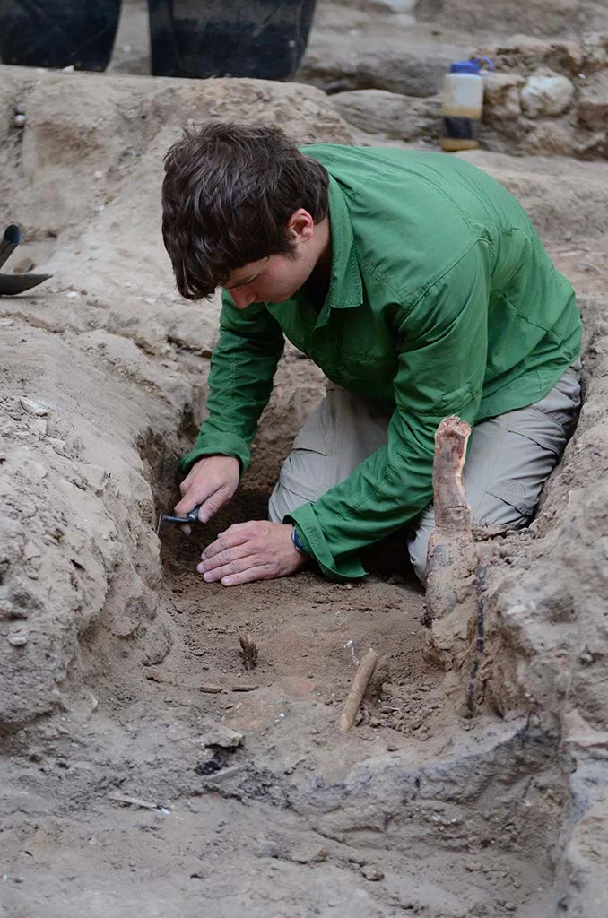 Chris works to expose some animal bones in Grid 51