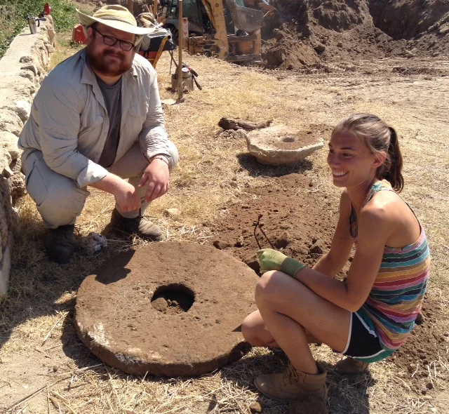 Staff examine a possible grinding stone found while preparing Grid 47