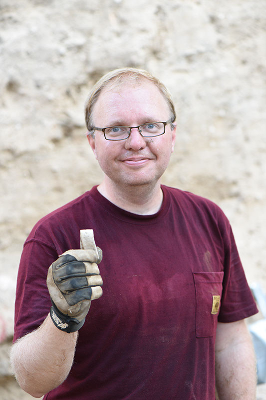 Kevin holds a piece of folded lead found in Grid 51