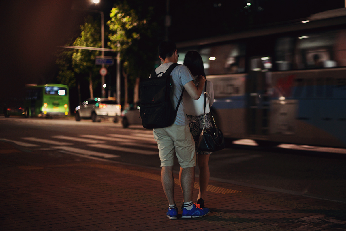A boy massaging his girl at the bus stop