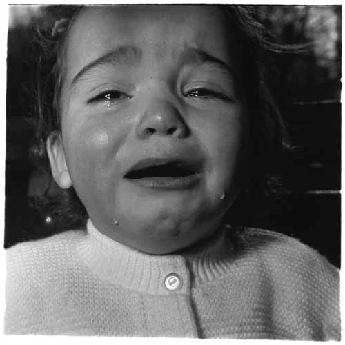 Diane Arbus, A child crying, N.J. 1967. ©The Estate of Diane Arbus We asked Tanya Marcuse to tell us about a picture that means something to her, and why. Her exhibition Woven is on view at the George Eastman Museum through January 5, 2020, and her new book Fruitless | Fallen | Woven (Radius Books) was published in July. It’s 1982, and I’m in the lower level of the library at Bard College at Simon’s Rock, where I started college early at 16. It wasn’t that I was precocious. Quite the opposite. I struggled my first semester, but I had begun to engage, to care. Second semester I’d hoped to take a drawing course, but it was full and, disappointed, I took photography instead. A few weeks in and I’m changed. A pile of nails spills on the floor – a magnet enters – all the nails point in one direction. I pull books off the shelf: Ansel Adams, Edward Weston, and then I see Diane Arbus. Her iconic 1972 posthumous Aperture monograph. I find A child crying, N.J. 1967 . There is no “composition,” no golden ratio, but a tight square frame of a girl sobbing. There are suggestions of a bigger world – a park bench, trees – but Arbus has zeroed in with attention, both tender and cold; the world inside the photograph is absolute, complete. The girl’s eyes brim over with tears that stream down her cheeks forming two distinct droplets. Each teardrop catches the light, has its own dimension. The child’s open mouth forms the darkest black of the photograph, a cavern. Her cry suggests a pain beyond a dropped ice cream cone or missed nap. The glints of light, first her eyes, then her tears, bring us to the sheen of a single button of her knit sweater fastened to the top. This small formality is a counterweight to the overflow of expression. I wasn’t very happy back then; I identified with the child (as well as with Arbus). But I saw that photography offered a language with the possibility of wholeness (oneness even) between form and content, expression and restraint, looking out and looking in. And that, for me, was salvific.
