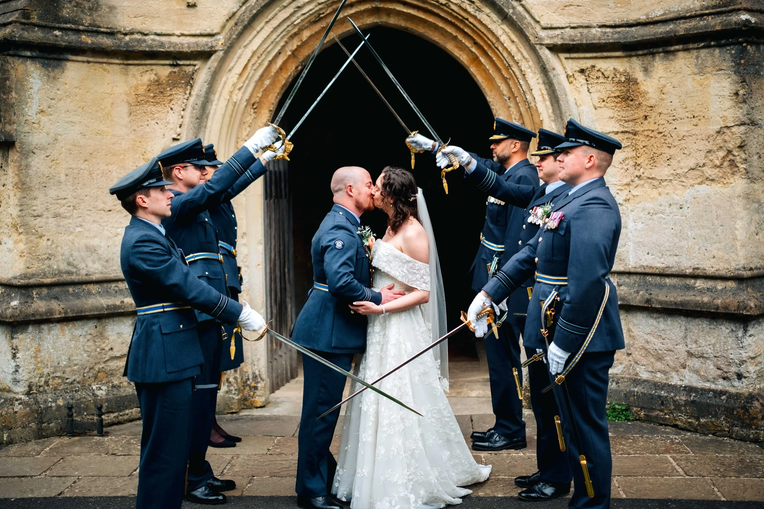 Military sword guard at Wiltshire church - bride and groom kissing