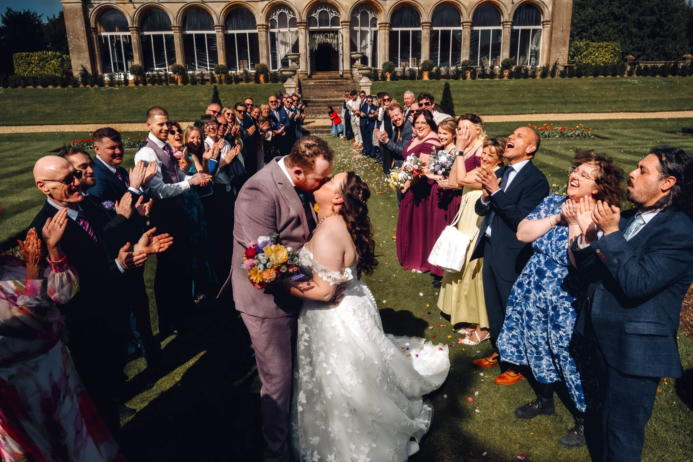 Bride and Groom share a kiss at the end of the confetti line at Grittleton House