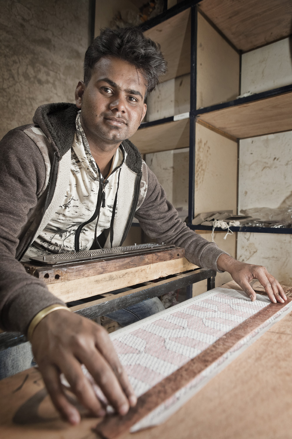  Portrait of master weaver Ganesh punching holes in the cards for the jacquard. 