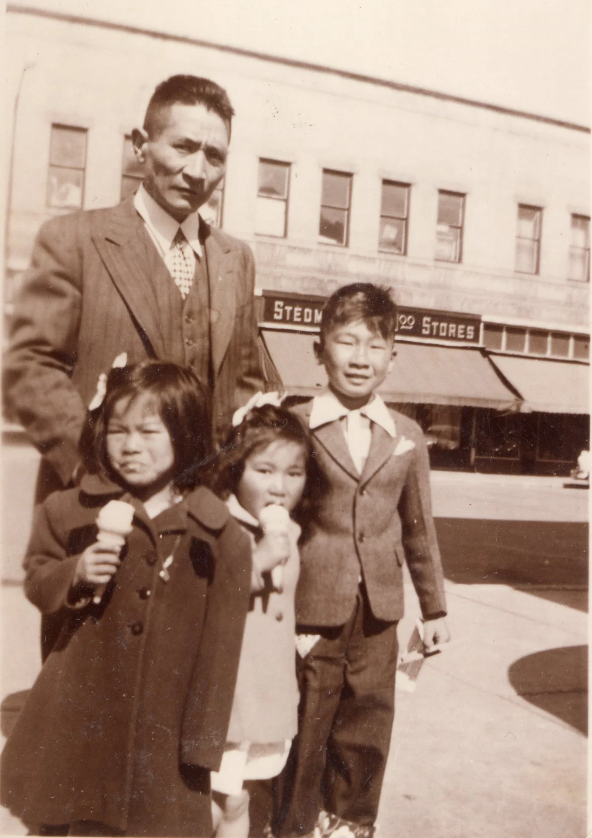 14267 Fred Okumura with his children Patsy, Ann and Ken. Stedaman Store in background. Mackenzie Ave.c1950s.jpg