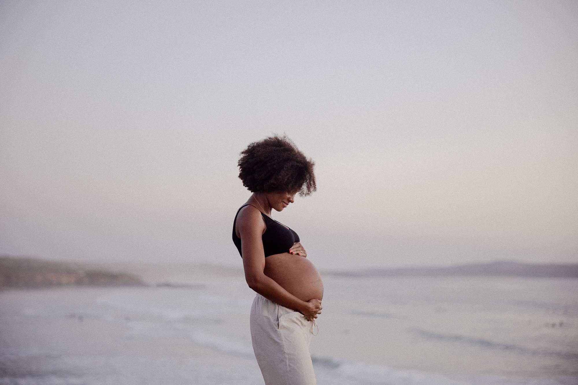 Pregnant woman posing at sunset overlooking the beach