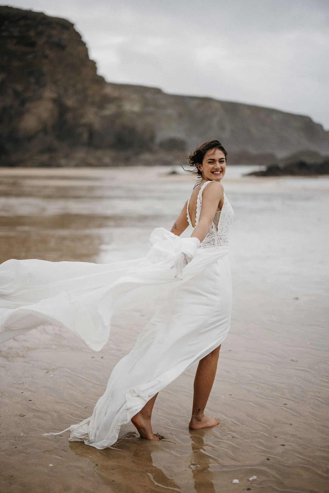 Bride running with dress blowing in wind on Lusty Glaze Beach