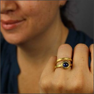 model wearing Blue sapphire cabochon (smooth domed cut) set in hammer textured 22K yellow gold