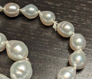 white drop shaped south sea pearl strand with frayed string that needs to be restrung