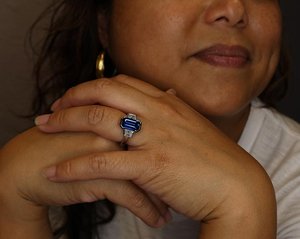 model wearing emerald cut blue sapphire engagement ring with trapezoid diamonds in platinum