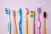 colorful toothbrushes on a pink background