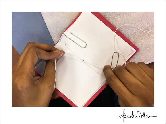 Tying the final knot in a pamphlet-stitch book.