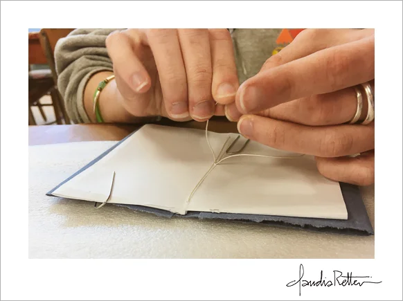 A student sewing a pamphlet binding.