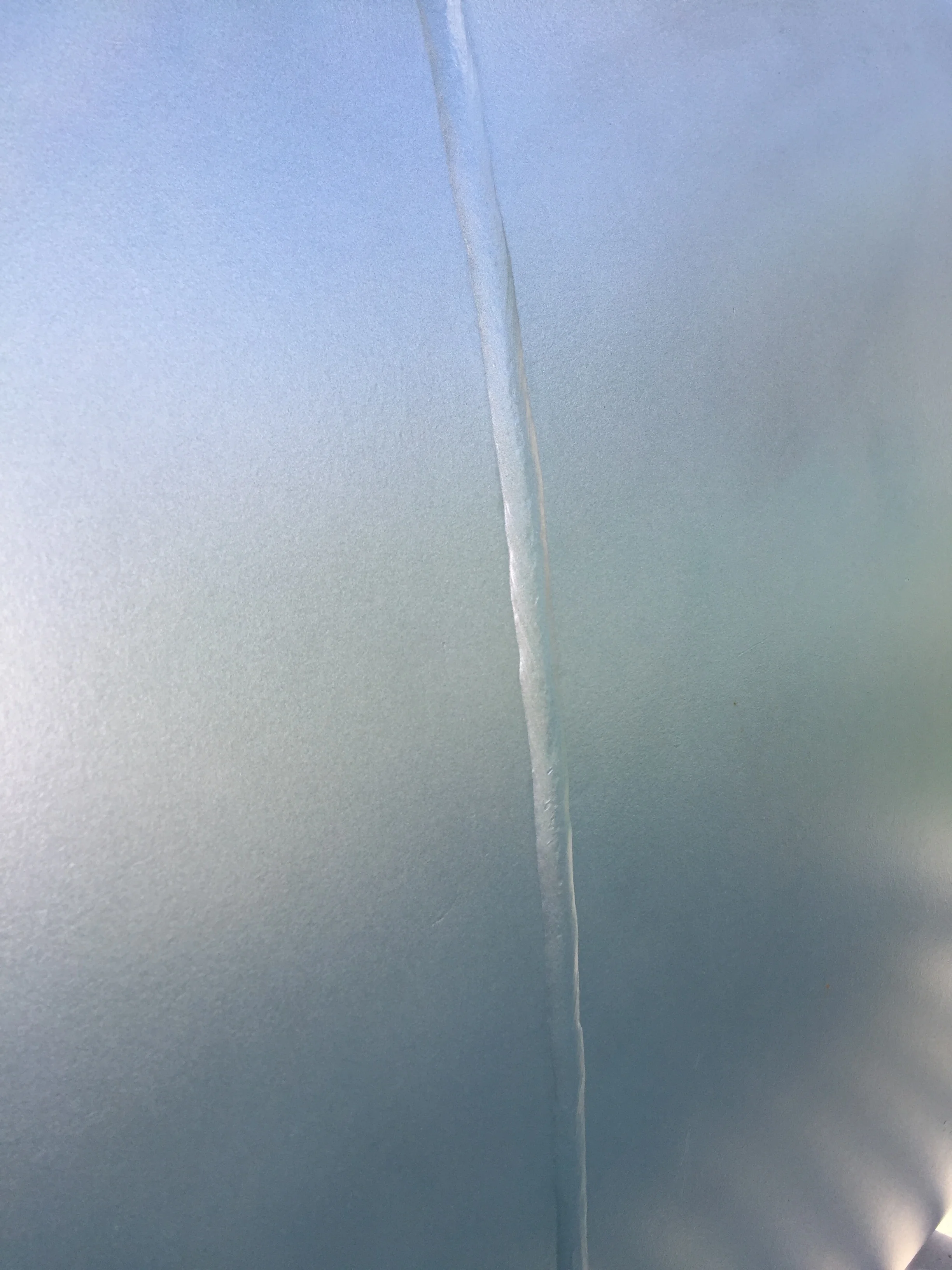 Close-up of a crack or scratch on a metallic or plastic surface.