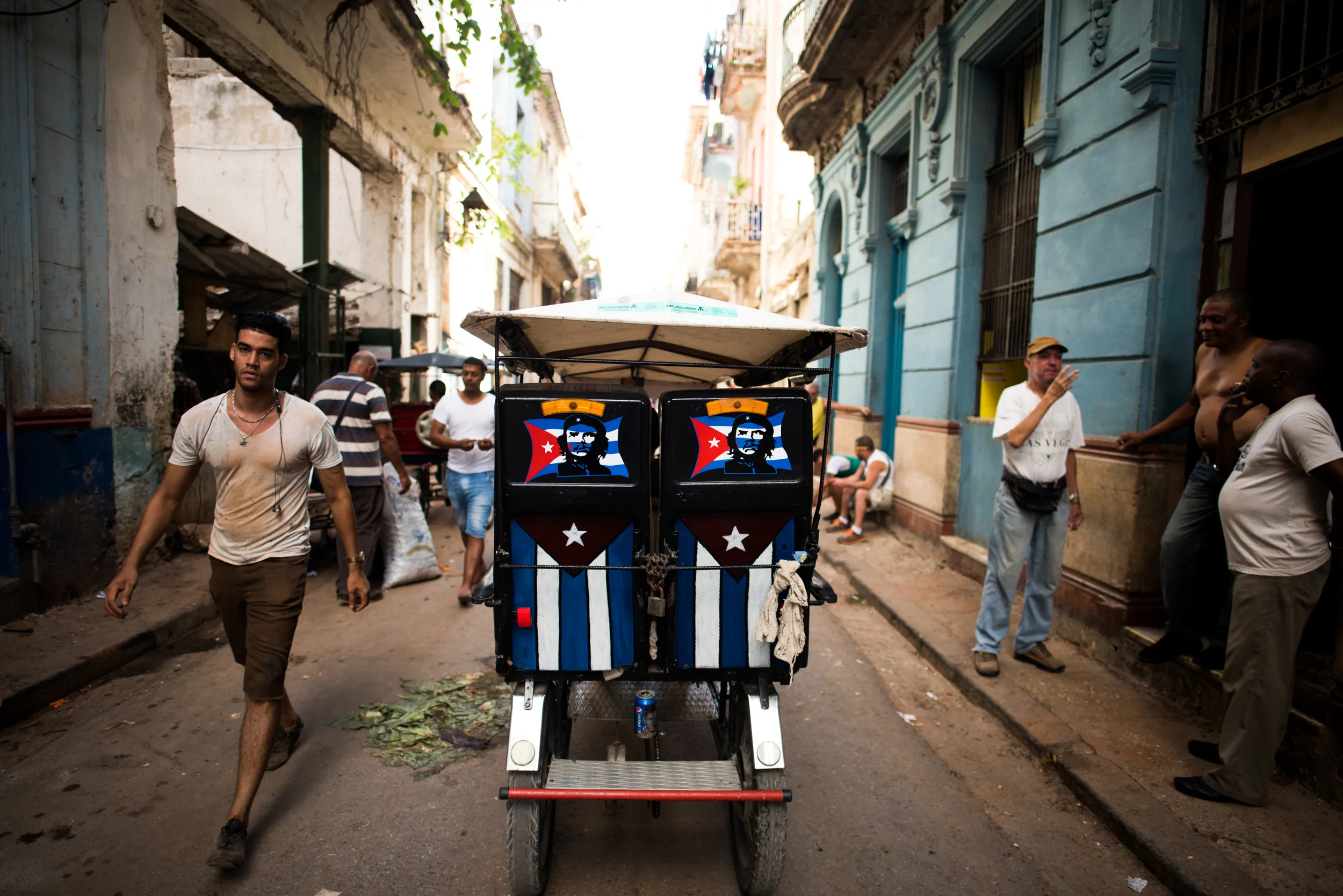 A pedicab with Cuban Flags and depictions of Che Guevara makes its way through a narrow street in Old Havana.