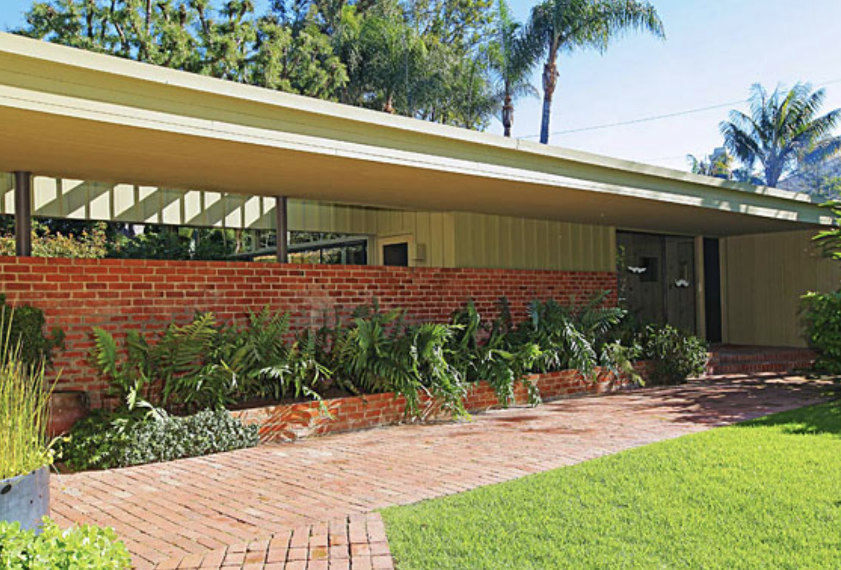 Richard Neutra's 1942 Nesbitt House in Brentwood, Los Angeles, showing its brick, redwood, and glass facade with reflecting pool.