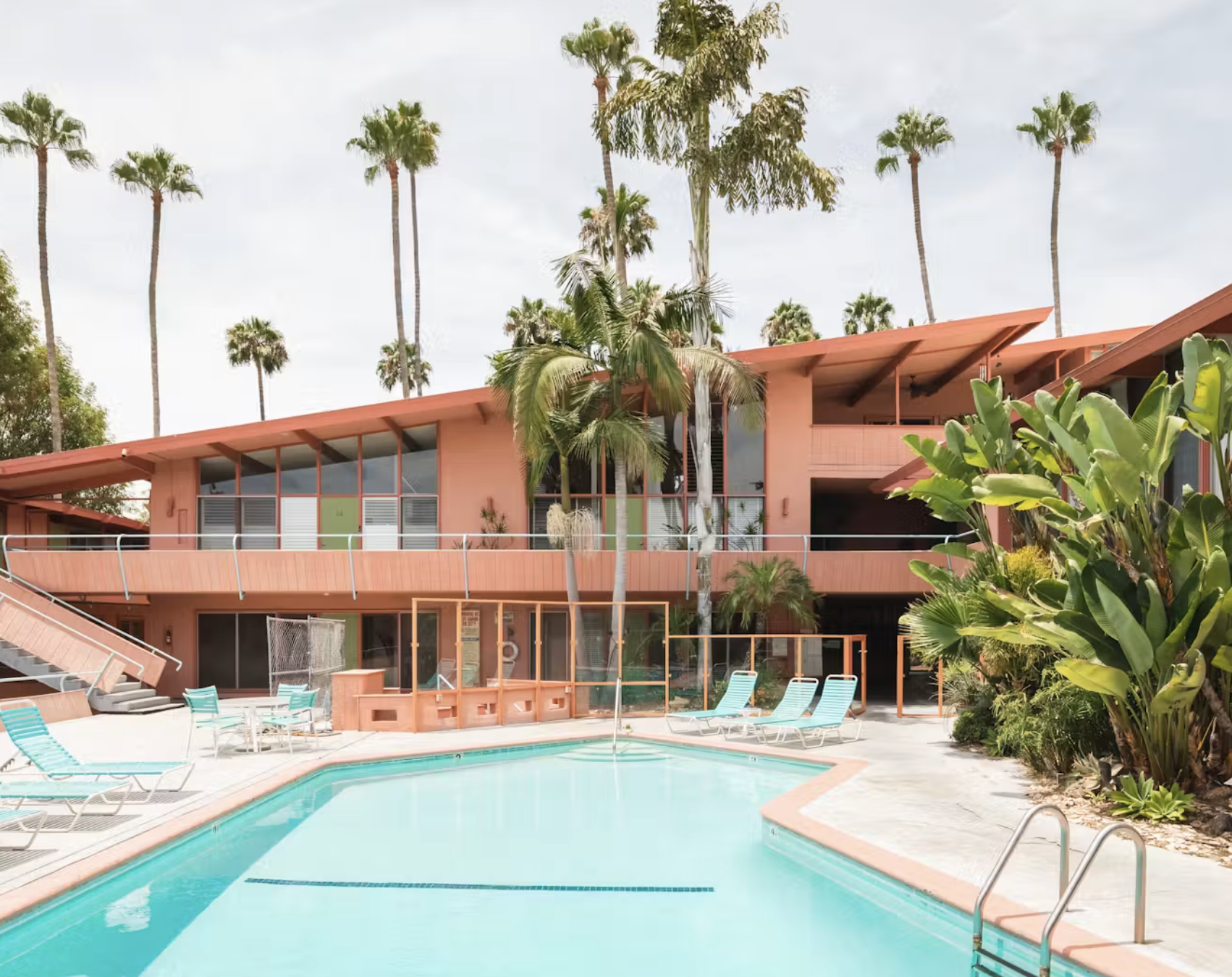 A mid century courtyard apartment building in West Hollywood, two stories of glass and low pitched roofs around a planted pool court
