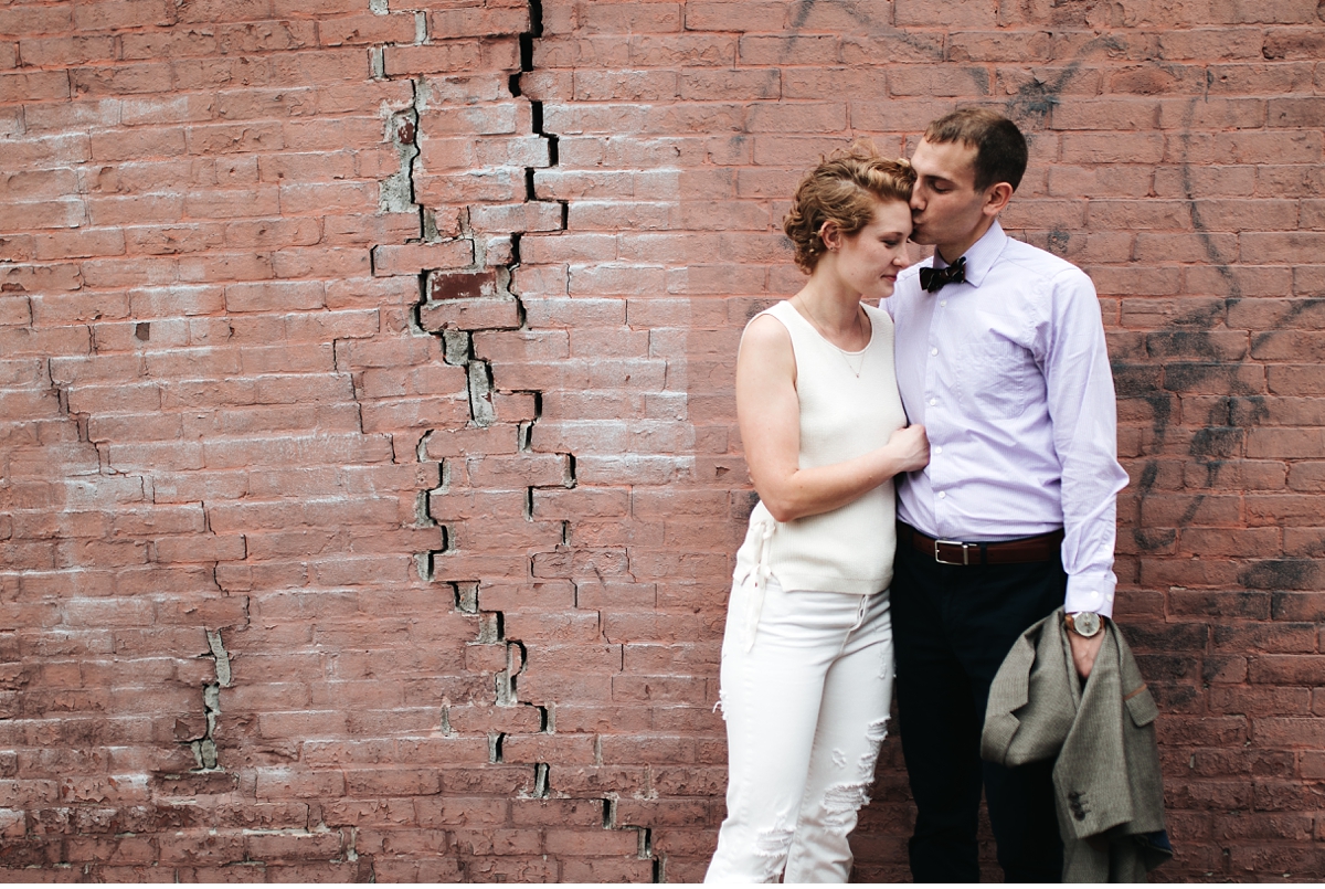 Man kissing financè's cheek against brick wall in Boston MA