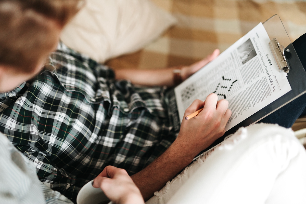 guy doing crossword puzzle in bed with fiancè