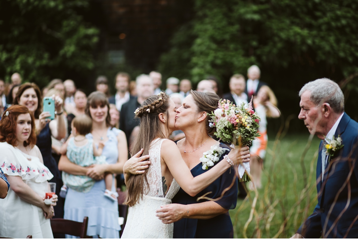 Bride kissing mom at end of isle during outdoor ceremony