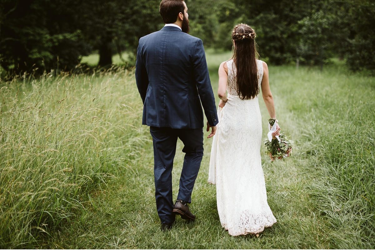 Bride and groom walking down grassy path