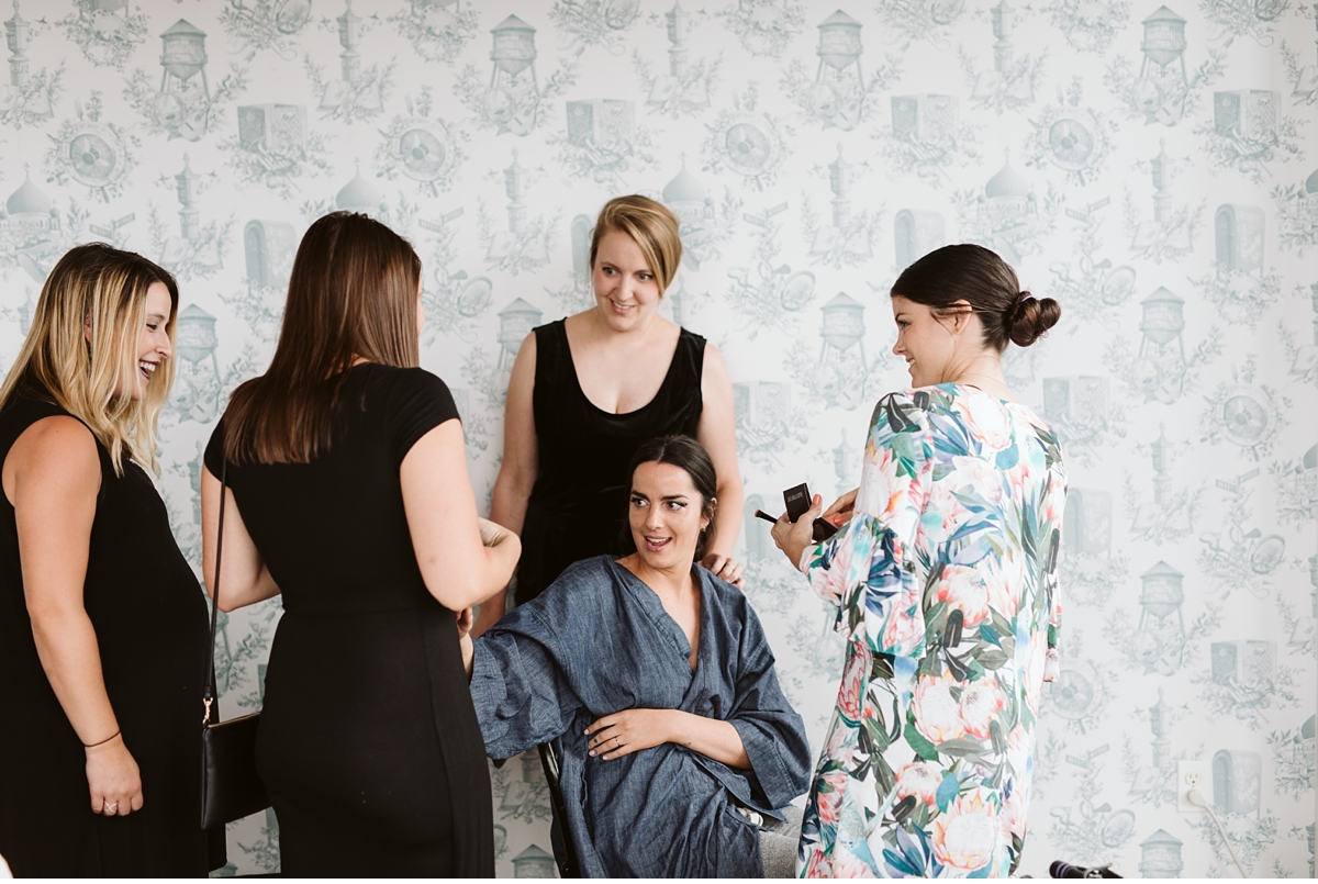 bride surrounded by friends in blue wallpaper room