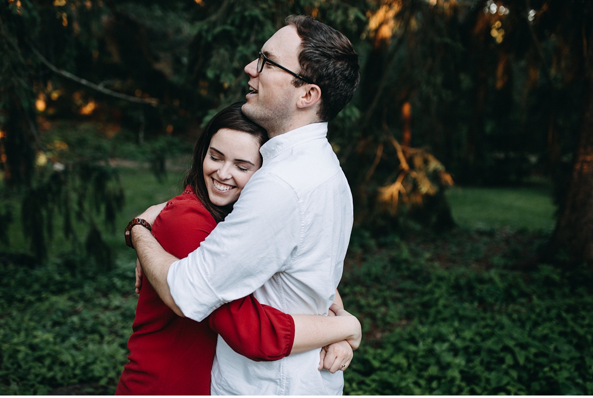 couple hugging surrounded by pine trees in the Arnold Arboretum