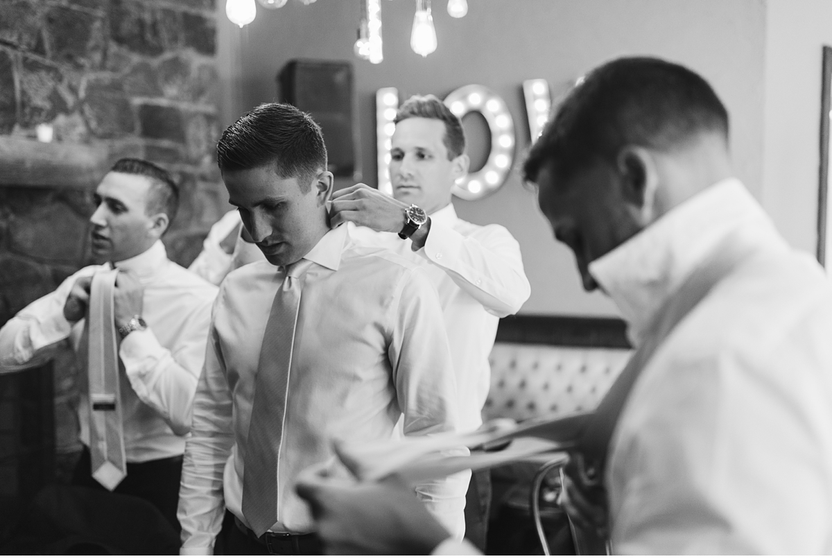 Groomsmen adjusting ties in black and white