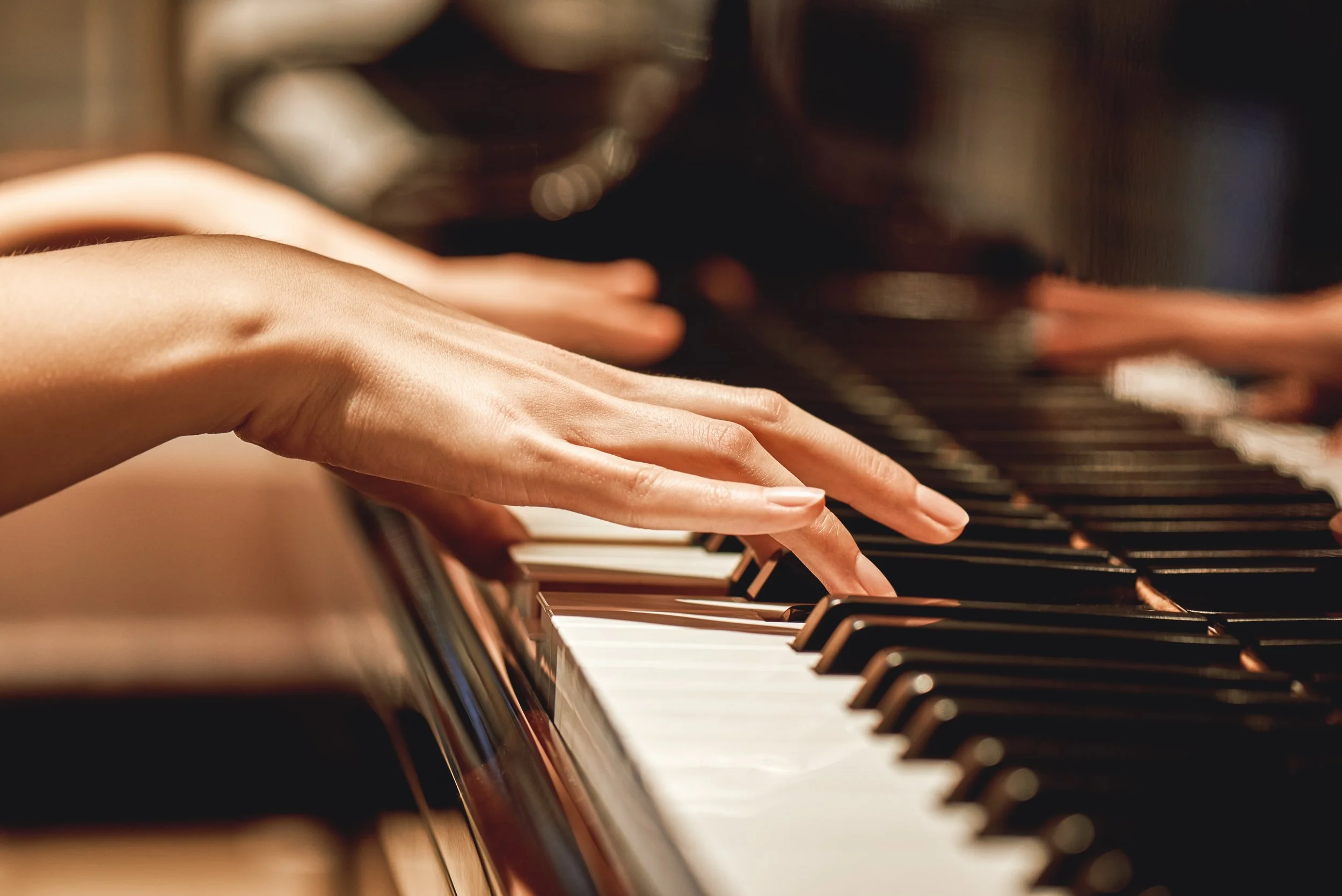 Close-up of hands playing a piano, representing piano lessons and music instruction by Tiffin Fuhrman in Minneapolis St. Paul