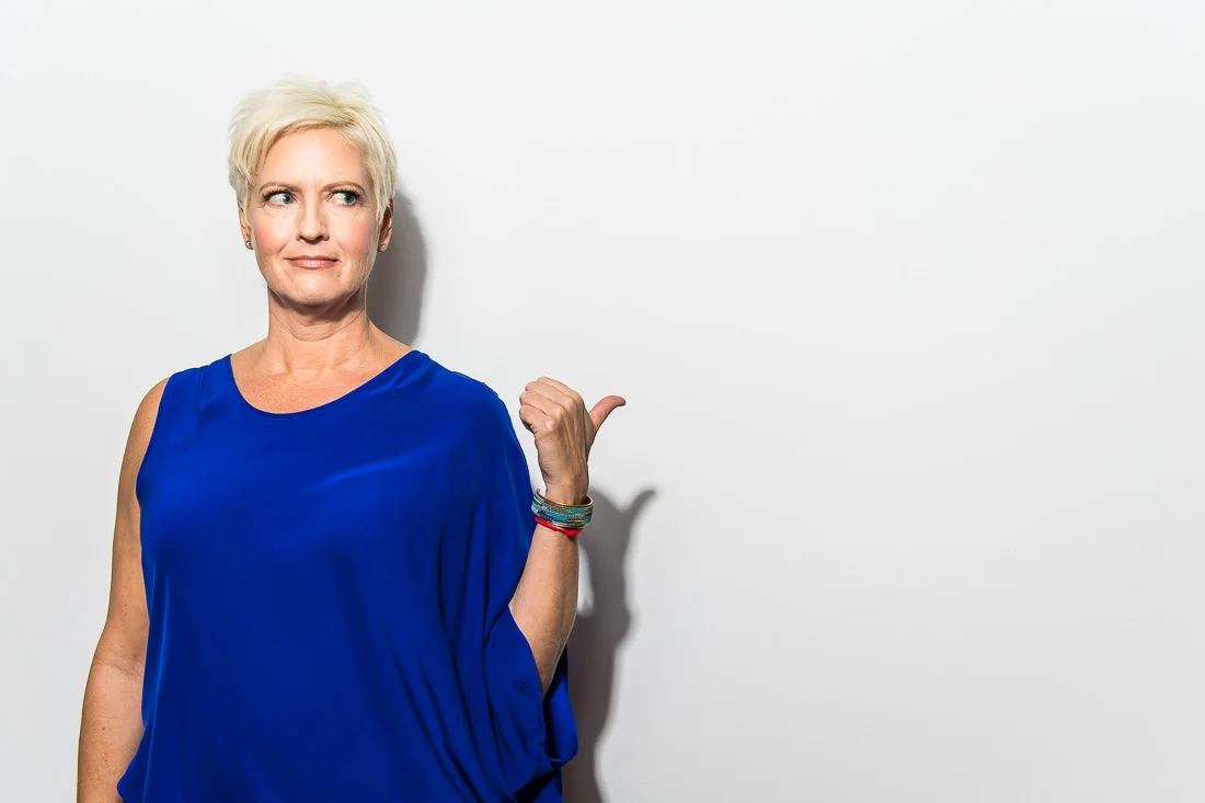 NYC Branded Lifestyle Portrait Speaker Coach Carolyn Herfurth pointing with her thumb off camera