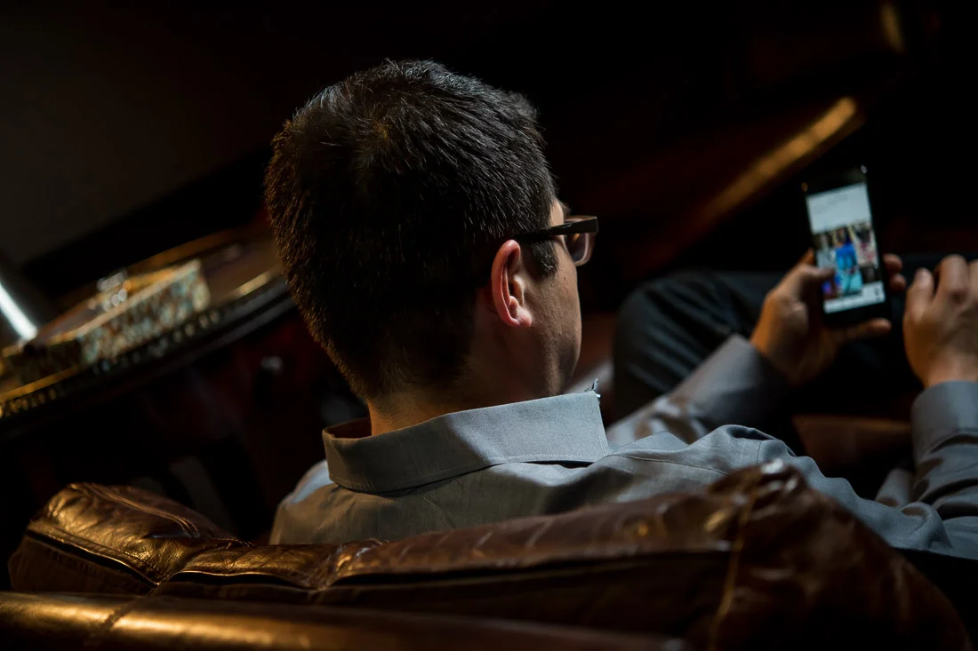 NYC Branded Lifestyle Portraits Cigar Merchant Luis Paredes looking at phone
