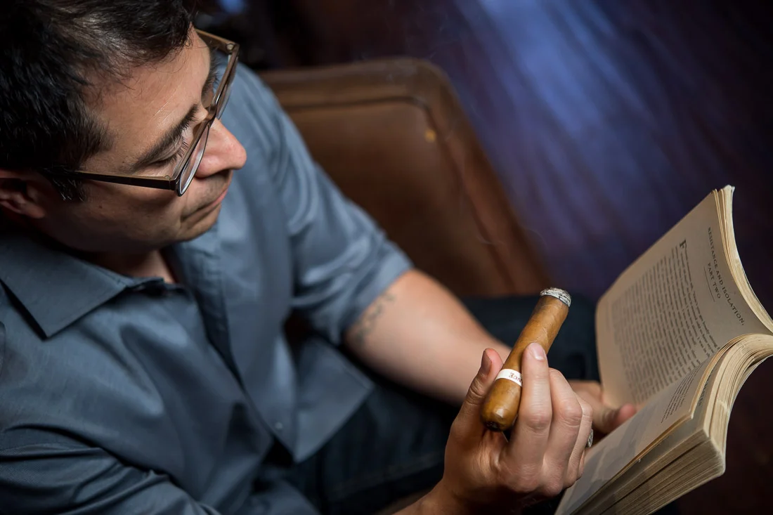 NYC Branded Lifestyle Portraits Cigar Merchant Luis Paredes reading a book cigar in hand